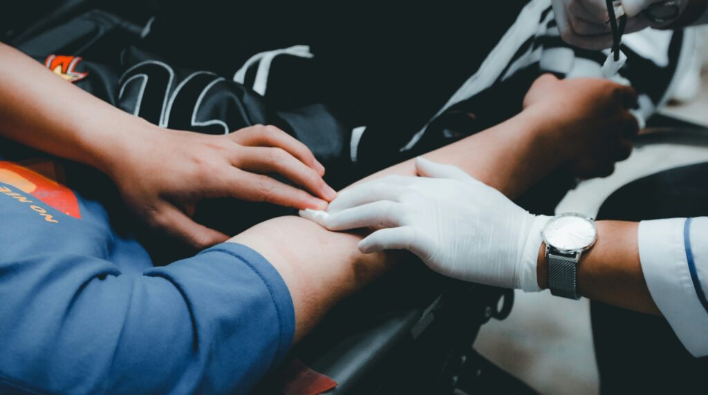 Healthcare professional wearing medical gloves treating a patient's arm